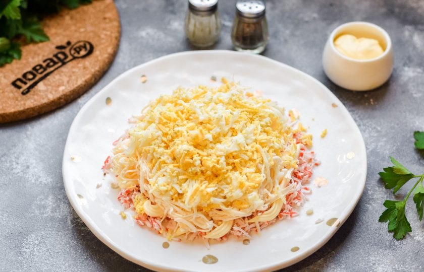 1. Этап. Тертый крабовый салат: Далее натрите куриные яйца на мелкой терке. Выложите яйца поверх сыра.