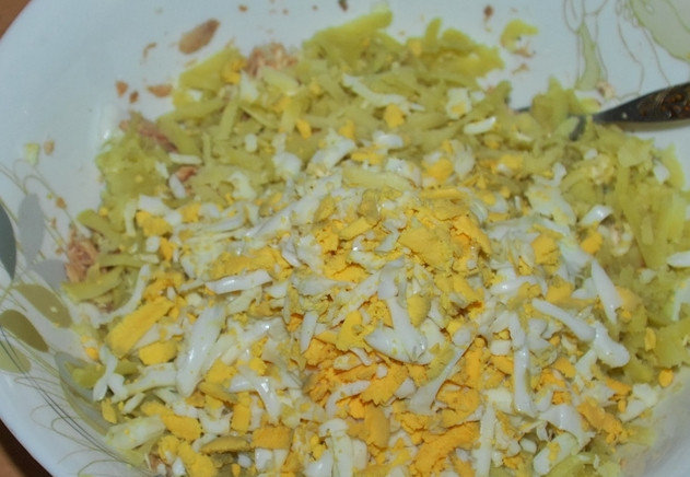 1. Этап. Cалат из рыбной консервы: Также добавьте яйца, предварительно очистив и натерев их на терке.