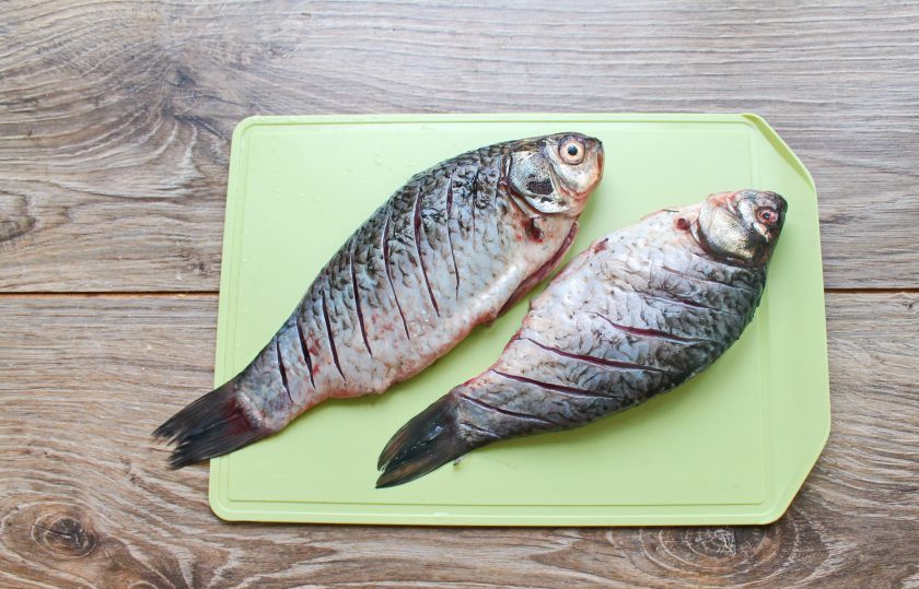 1. Этап. Караси в сметане в духовке в фольге: У карасей отстригите плавники, удалите чешую, внутренности и жабры. Промойте карасей, обсушите бумажным полотенцем и сделайте косые надрезы, не прорезая крупные кости, наискосок по всей поверхности тушки с двух сторон.