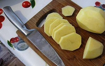 1. Этап. Говядина с овощами и грибами: При помощи ножа очищаем картошку от кожуры и хорошо промываем под проточной водой. Просушиваем картофель с помощью бумажного полотенца и перекладываем его на разделочную доску. При помощи ножа нарезаем корнеплоды поперек на небольшие по толщине кусочки, чтобы они запеклись одновременно с мясом и не пригорели у основания противня.