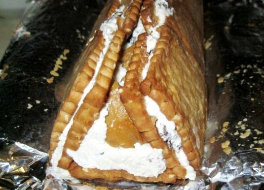 1. Этап. Торт с печеньем и творогом: 7. Возьмитесь за края пергамент и аккуратно сложите крайние стороны в форме треугольника, как бы формируя избу. Отправьте торт в холодильник в таком виде.