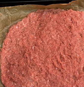 1. Этап. Очень мясная пицца-запеканка: Противень застелить пергаментом. Равномерно распределить на нем основу для пиццы. Лучше это делать руками, смоченными водичкой