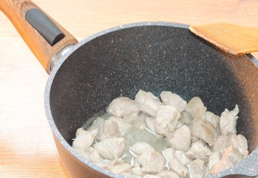 1. Этап. Поджарка с подливкой и лапшой: 5. Возьмите сковороду с толстым дном и высокими стенками или ковш, как у меня. Налейте растительное масло и хорошо нагрейте на среднем огне. Можно добавить немного сливочного — для вкуса. Положите в разогретое масло кусочки свинины. Жарьте до бела, периодически их переворачивая, минут 5.