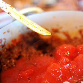 1. Этап. Говядина в болонском соусе: Кладем консервированные помидоры в кастрюлю.