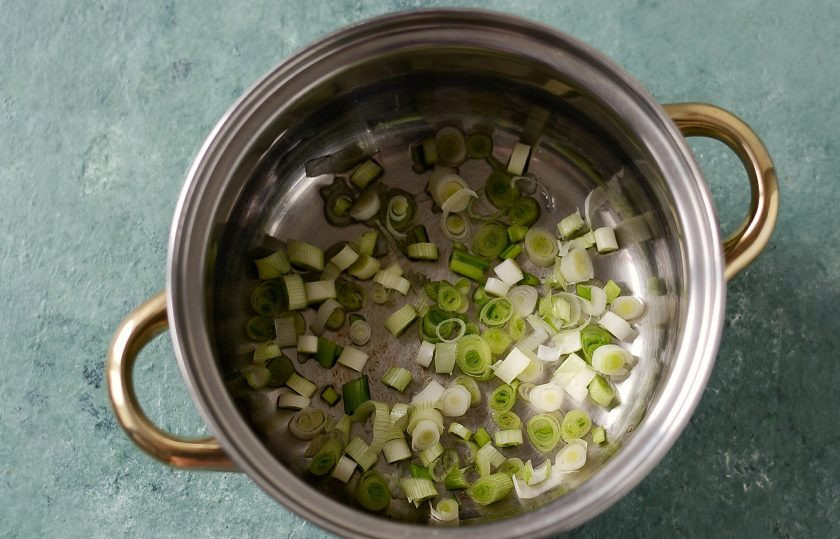 1. Этап. Суп из тыквы и шпината: Мелко порубите белую часть зеленого лука, обжарьте до мягкости в небольшом количестве масла.