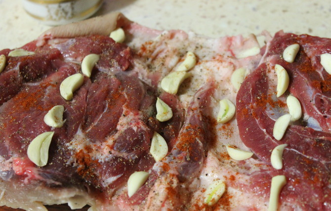 1. Этап. Ветчина из рульки: Внутрь засыпаем перец, кориандр, паприку. Раскладываем по рульке чеснок.