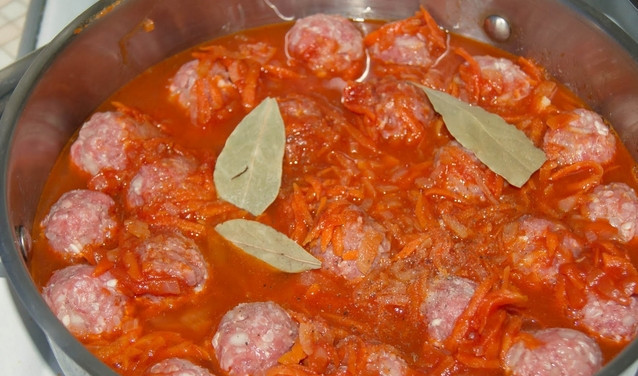 1. Этап. Ежики под соусом: Перекладываем их в сотейник и заливаем томатным соусом, также вливаем воду и добавляем лавровые листы.