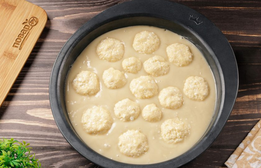 1. Этап. Заливной пирог на кефире с творогом: Жаропрочную форму смажьте маслом. Вылейте тесто и разровняйте. Из творога сформируйте небольшие шарики, можно разного размера и выложите сверху на некотором расстоянии друг от друга.