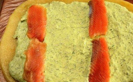 1. Этап. Сырный рулет с семгой: Затем на теплый пласт сыра выкладываем зеленую творожную массу, оставляя края пустыми, а затем раскладываем тонкие ломтики семги.