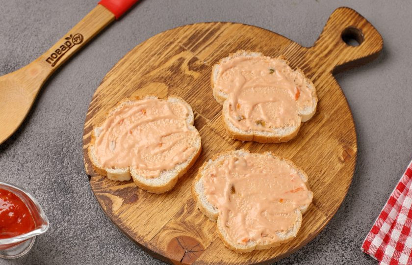 1. Этап. Мини-пицца на батоне в духовке: В качестве намазки лучше всего взять кетчуп и майонез в равных пропорциях. Соедините и перемешайте. Смажьте соусом кусочки батона.