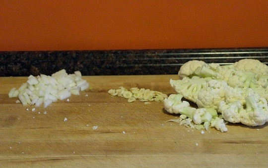 1. Этап. Сливочный суп с цветной капустой: 1. Очистите и измельчите лук с чесноком. Вымойте, обсушите, разделите на соцветия цветную капусту. В кастрюле разогрейте растительное масло.