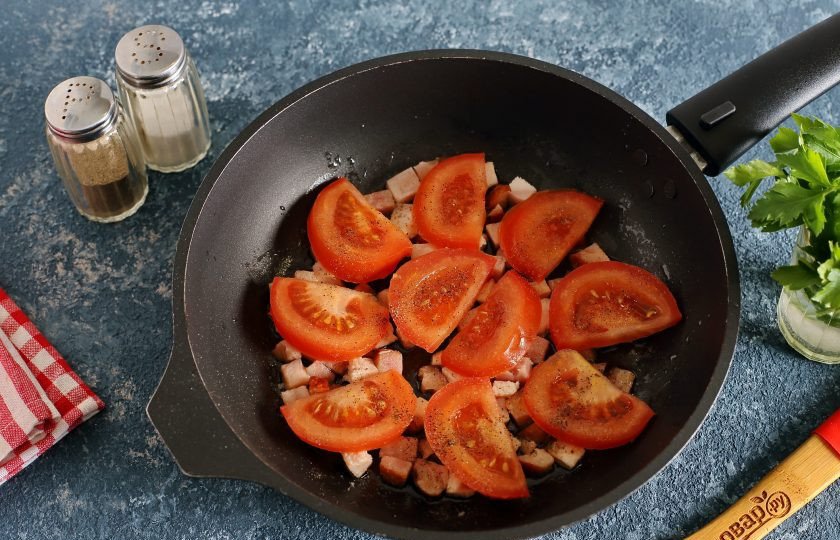 1. Этап. Яичница с бужениной: Слегка обжарьте в течение 1-2 минут и сверху равномерно распределите помидоры, нарезанные дольками или кружками. Посолите и поперчите по вкусу.