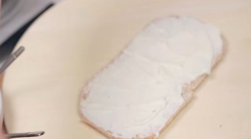 1. Этап. Сэндвич-торт Джейк из Время приключений: 3. Приготовьте заправку: сливочный сыр смешайте со сметаной. Добавьте соль, перец и специи по вкусу (можно добавить кинзу или базилик). Из первого слоя хлеба сформируйте основу для торта в виде прямоугольника и смажьте его заправкой.