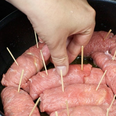 1. Этап. Рулетики из телятины: В сковороде разогрейте небольшое количество масла. Аккуратно выложите в нее рулетики и обжарьте до легкой корочки с одной стороны.