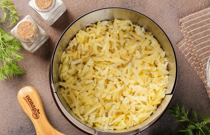 1. Этап. Салат Шпротка: Я буду выкладывать салат при помощи кулинарного кольца, но можно просто выложить его слоями в любой глубокий салатник. Первым слоем выложите тёртый картофель. Посолите, поперчите и смажьте слой майонезом.