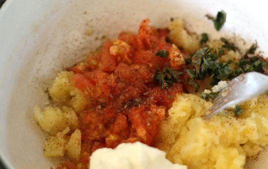 1. Этап. Запеченный картофель с начинкой: Далее готовим начинку. Вырезанную часть картофелей размельчить. К пюре добавить порубленный базилик, нарезанные помидоры без кожуры, сметану, также в начинку выдавить чеснок. Все хорошенько перемешать.