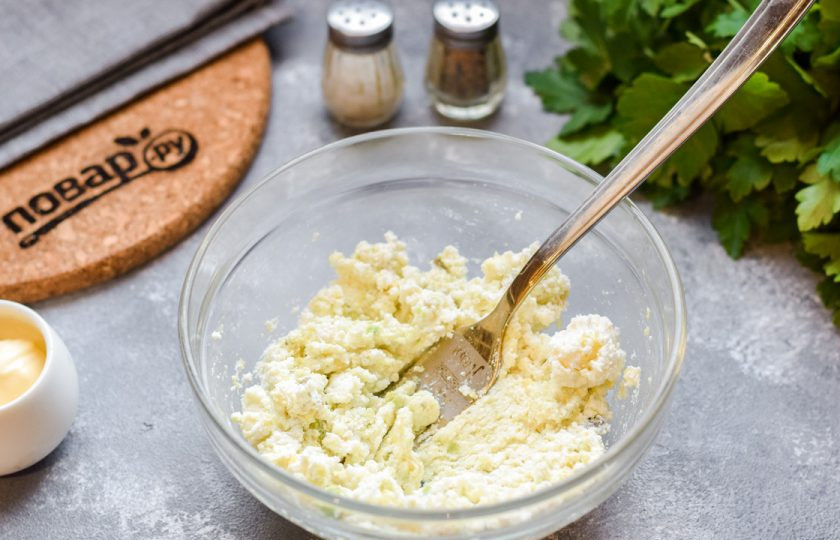 1. Этап. Тарталетки с авокадо и крабовыми палочками: Перемешайте творог и авокадо, разотрите ингредиенты между собой.