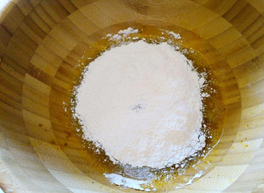 1. Этап. Кабачковые наггетсы в духовке: Всыпьте в яичную массу 100 грамм просеянной муки и размешайте до однородности.