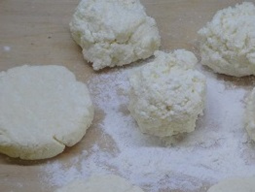 1. Этап. Сырники с апельсиновым соусом: У меня из этой массы получается 9 сырников весом по 50 г. Формируем сырники на припыленной мукой доске с помощью ножа.