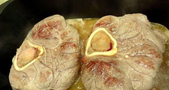 1. Этап. Тушеная голяшка: Разогрейте сковороду с оливковым маслом. Обжарьте мясо до румянца, а потом залейте вином. Дать закипеть, затем уменьшите огонь, половина вина должна увариться.