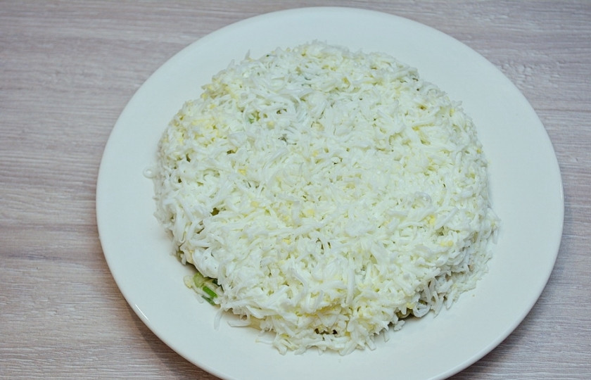1. Этап. Новогодний салат Куранты: 7. Отложенные желтки натрите на мелкой терке. Верхнюю часть салата закройте белками. Распределите равномерно.