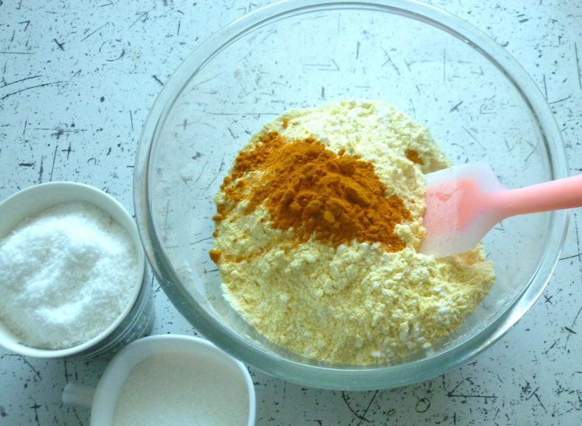 1. Этап. Веганский пирог с кокосом: Добавьте куркуму, сахар и кокосовую стружку. Для выпечки лучше брать мелкий сахар. Перемешайте.