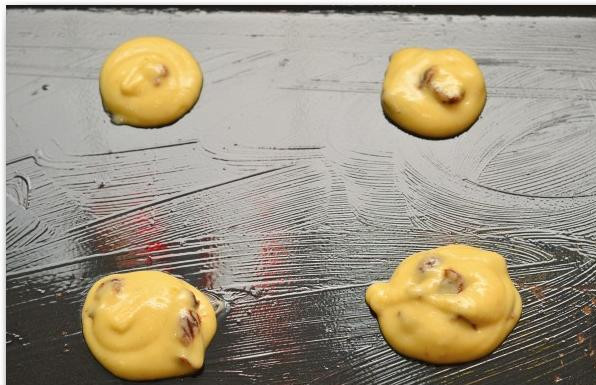 1. Этап. Печенье с ромом и изюмом: Берем противень, хорошенько смазываем его растопленным сливочным маслом. Смесь кладем в кулинарный мешок и выдавливаем небольшими порциями на противень на расстоянии хотя бы в пару сантиметров друг от друга.