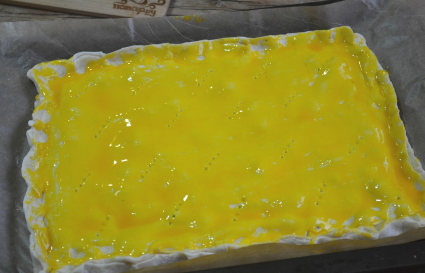 1. Этап. Пирог с малиной из слоеного теста: Накройте вторым листом слоеного теста, сверху смажьте взбитым яйцом или желтком. По всей поверхности сделайте 8-10 проколов вилкой.