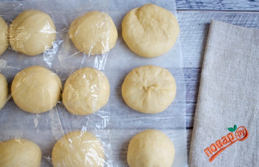 1. Этап. Булочки Даугавиня: Взвесьте тесто и разделите его на 12 равных частей. У меня получилось по 80 г. Каждую заготовку отбейте основанием ладони в круглую лепешку, убирая лишний газ. Соберите тесто от края к центру, прижимая пальцем, переверните узелком вниз. Положите сверху ладонь, вращайте против часовой стрелки. С помощью такого округления заготовки у вас получатся булочки с воздушным мякишем, с равномерными мелкими дырочками.