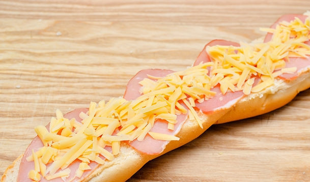 1. Этап. Бутерброды с багетом: Смажьте багет тонким слоем майонеза или соуса, уложите ветчину, а сверху посыпьте тертым сыром.