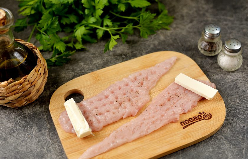 1. Этап. Куриные рулетики с плавленым сыром в беконе: Каждую полоску курицы посолите и слегка поперчите, выложите тонкий брусочек плавленого сыра, скрутите заготовку рулетиком.