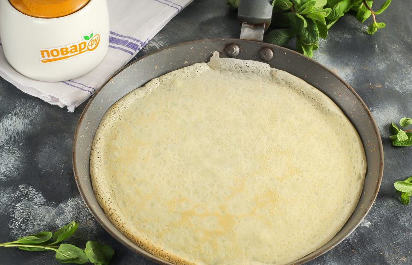 1. Этап. Блинная кутья с маком, изюмом и орехами: Прогрейте сковороду на плите и смажьте в первый раз растительным маслом. Уменьшите нагрев до умеренного и влейте половину половника теста. Округлите тесто на сковороде и испеките румяный блин по 1-2 минуты с каждой стороны. Таким образом испеките все блины.