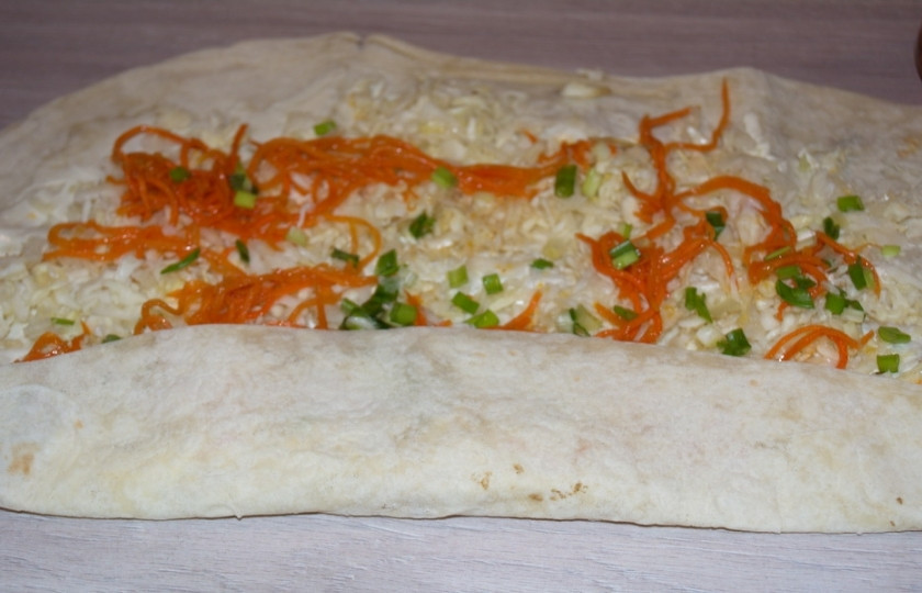 1. Этап. Овощной рулет из лаваша: Сверните лаваш в рулет. Если вы используете пленку, то она поможет сдержать тонкий пласт лаваша, что в свою очередь не допустит появления разрывов в лаваше.