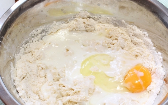 1. Этап. Осетинский пирог Балджин: Добавьте яйцо, кефир, растопленное, но уже остуженное сливочное масло (40-50 г), приступайте к замесу. Вымешивайте тесто до мягкого состояния, при необходимости подсыпьте муку.