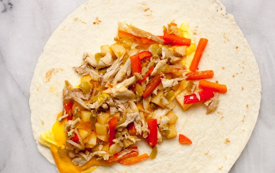 1. Этап. Мексиканский бурито: Для соуса взбейте яйцо с 0,5 столовой ложки воды, добавьте тертый сыр, прогрейте в микроволновке пару секунд и перемешайте до однородности. На лепешку выложите соус и уложите продукты со сковороды.