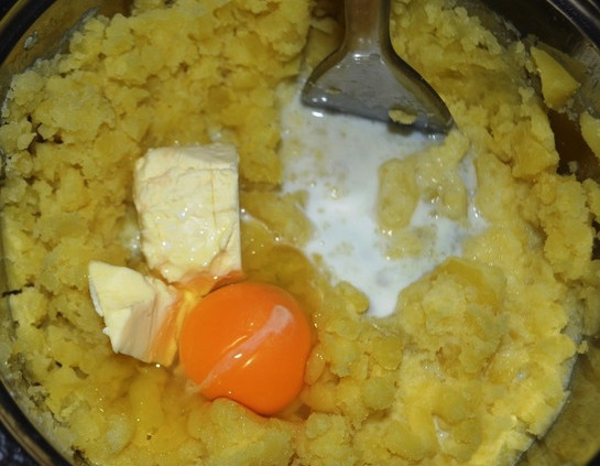 1. Этап. Картофельные гнезда: Картофель очистите и отварите до готовности в подсоленной воде. Обычно это занимает около 20-25 минут. Затем слейте воду и добавьте к картофелю молоко и яйцо. Теперь картофель разомните толкушкой в нежное пюре.