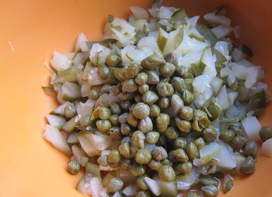 1. Этап. Солянка колбасная: 4. Мелко нарежьте соленые огурчики. Добавьте их в кастрюлю вместе с каперсами примерно через 10 минут. Положите лавровый листик.