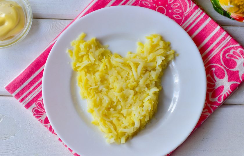 1. Этап. Новогодний салат Крысенок: Выложите в форме крысы на блюдо натертый на крупной терке вареный картофель.