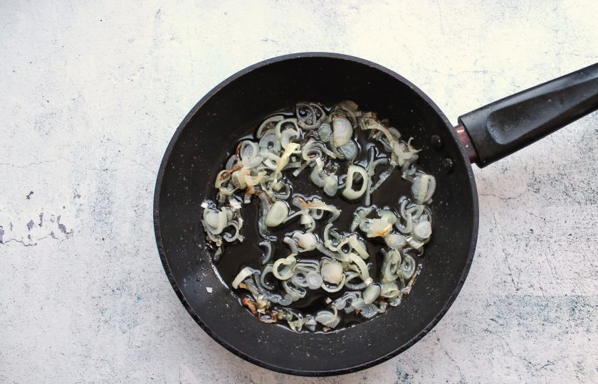 1. Этап. Жареные пельмени с луком на сковороде: Репчатый лук порежьте и обжарьте в растительном масле в течение 2 минут на среднем огне.