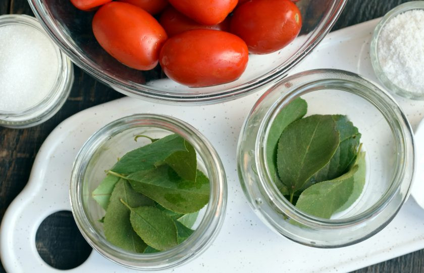 1. Этап. Помидоры с вишневыми листьями на зиму: Листья вишни обдайте кипятком. Часть листьев выложите на дно банки. Тонкие веточки можно, как удалить, так и оставить.