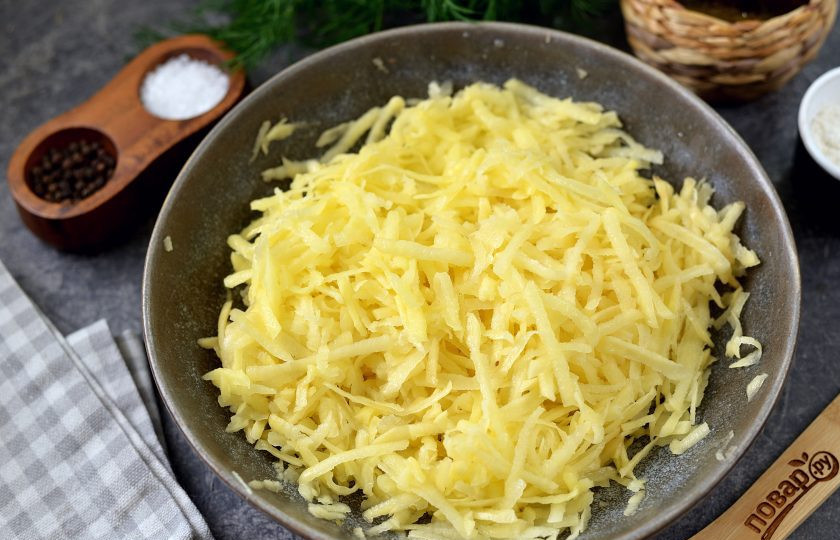 1. Этап. Драники с беконом и крабовыми палочками: Картофель натрите на крупной терке, отожмите лишнюю жидкость, переложите в глубокую миску.