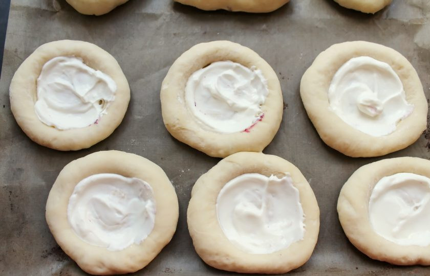 1. Этап. Ватрушки с черникой: Разложите сметану по всем углублениям и разровняйте.