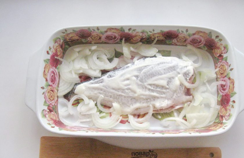 1. Этап. Лещ в духовке с картофелем: Репчатый лук нарежьте полукольцами и разложите вокруг рыбы.