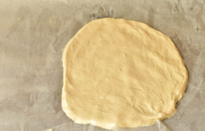 1. Этап. Дрожжевой пирог с красной рыбой: Разделите дрожжевое тесто пополам. Половину выложите на противень, который застелите пергаментной бумагой.