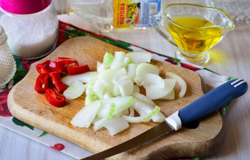 1. Этап. Салат из огурцов с перцем и луком на зиму: Почистите репчатый лук, перец чили сполосните. Лук нарежьте полукольцами, а перец чили колечками.