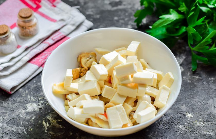 1. Этап. Салат Кальмаровый пир: Плавленый сыр нарежьте небольшими кубиками, переложите в салат.