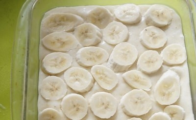 1. Этап. Бразильский банановый пирог: Выкладываем половину теста в форму, слегка смазанную растительным маслом, а затем уложите нарезанные кружочками бананы. Сверху посыпаем половиной песочной крошки.