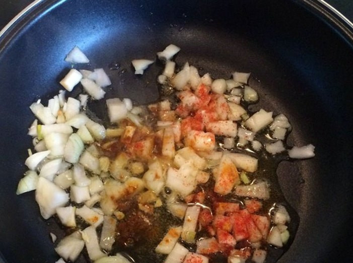 1. Этап. Тушеная капуста с помидорами: В разогретую сковороду влейте масло. Выложите в неё лук, добавьте к нему паприку и куркуму. Готовьте на среднем огне до золотистого цвета.