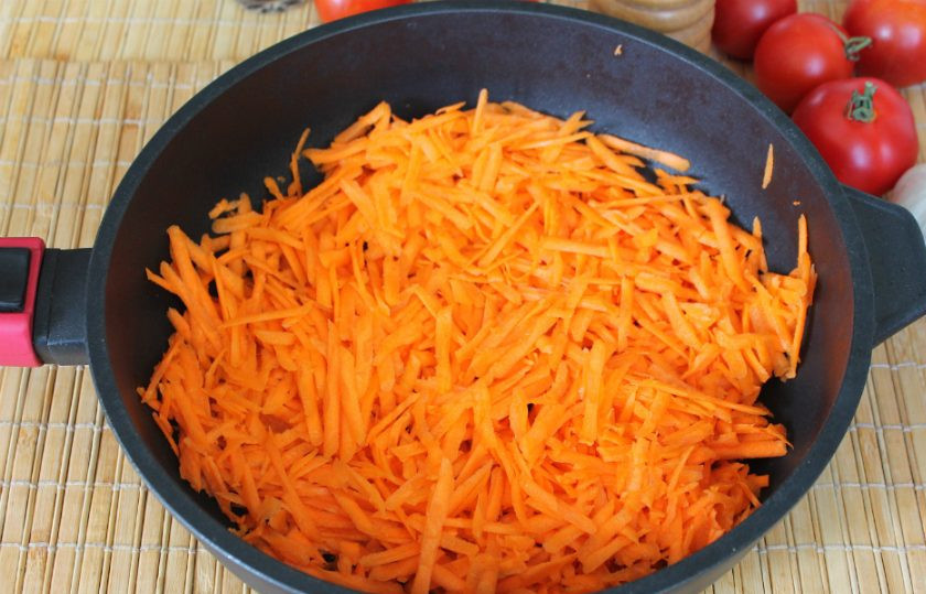 1. Этап. Перец фаршированный морковью на зиму: На сковороду наливаем подсолнечное масло и высыпаем тертую морковь. Обжариваем 10 минут на среднем огне, периодически перемешивая.