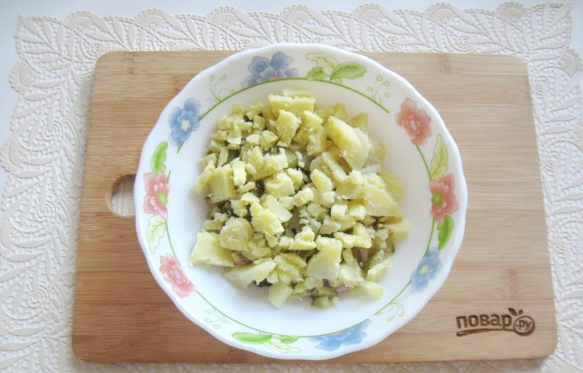 1. Этап. Салат со свининой и солеными огурцами: Картофель отварите, остудите и очистите. Нарежьте кубиками и выложите в салат.